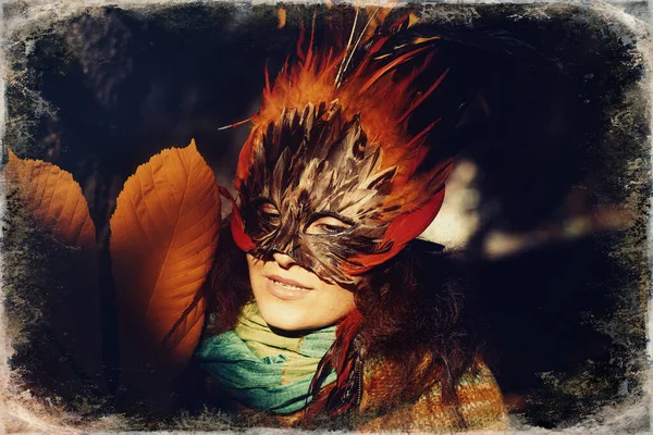 Ung kvinna med en färgglad fjäder ansikte mask, gamla foto effekt. — Stockfoto