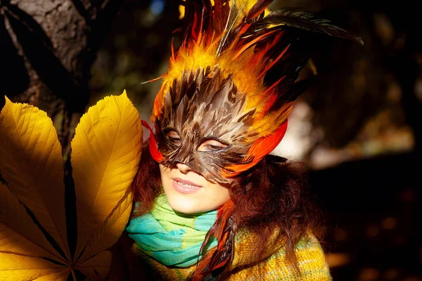 Young woman with a colorful feather face mask. — Stock Photo, Image