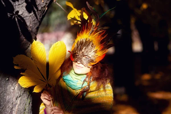 Mladá žena s barevnou péřovou obličejovou maskou. — Stock fotografie