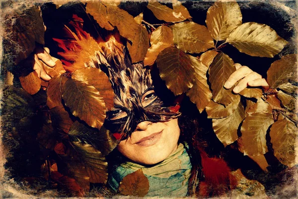 Ung kvinna med en färgglad fjäder ansikte mask, gamla foto effekt. — Stockfoto