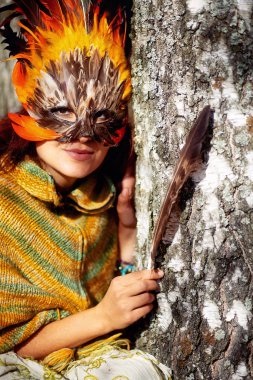 Renkli tüylü maskeli genç bir kadın..