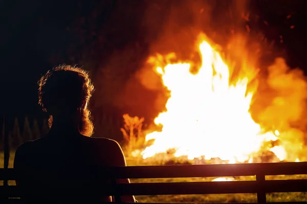 Mann Sitzt Feuer Und Blickt Auf Die Flamme — Stockfoto