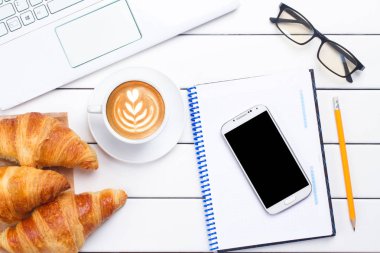 kahve kruvasan telefon laptop görünümü beyaz arka plan yukarıda