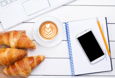 kahve kruvasan telefon laptop görünümü beyaz arka plan yukarıda