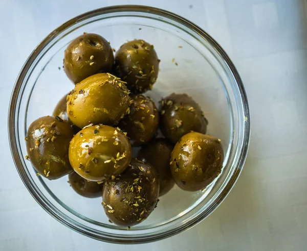 Green olives with spices in glass bowl — Stock Photo, Image