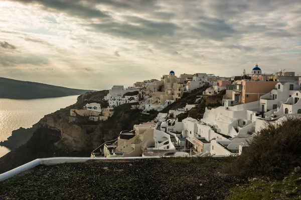 White city on a slope of a hill at sunset, Oia, Santorini, Greec
