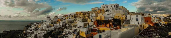 White city on a slope of a hill at sunset, Oia, Santorini, Greec