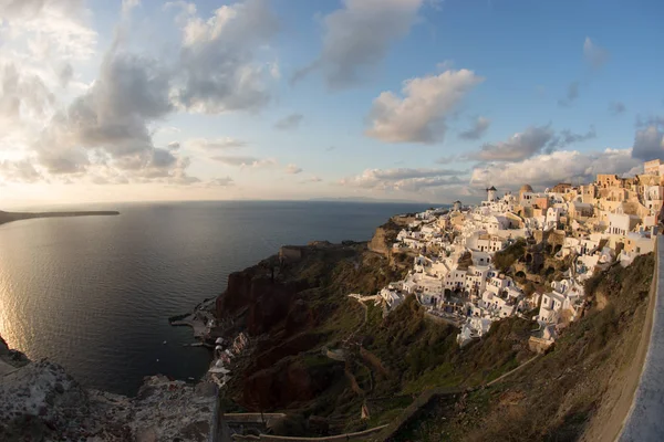 White city on a slope of a hill at sunset, Oia, Santorini, Greec