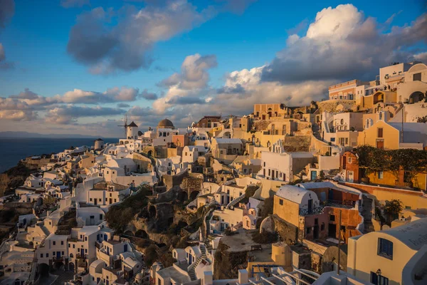 White city on a slope of a hill at sunset, Oia, Santorini, Greec