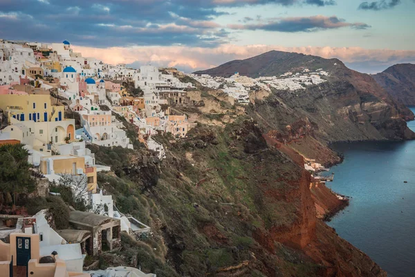 White city on a slope of a hill at sunset, Oia, Santorini, Greec