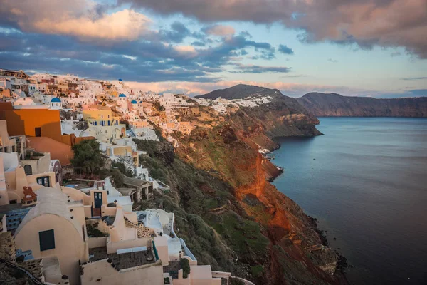 White city on a slope of a hill at sunset, Oia, Santorini, Greec