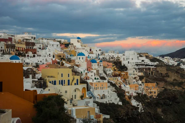 White city on a slope of a hill at sunset, Oia, Santorini, Greec