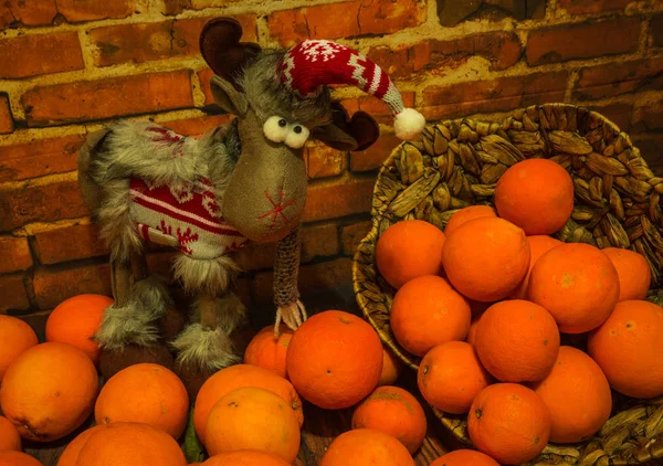 Christmas reindeer and  pile of oranges at  brick wall — Stock Photo, Image