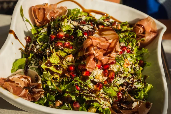 Insalata verde con prosciutto, melograno, formaggio e salsa speciale — Foto Stock