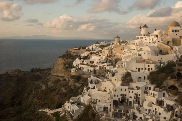 White city on a slope of a hill at sunset, Oia, Santorini, Greec