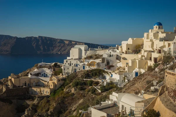 White city on a slope of a hill at sunset, Oia, Santorini, Greec