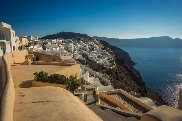 White city on a slope of a hill at sunset, Oia, Santorini, Greec