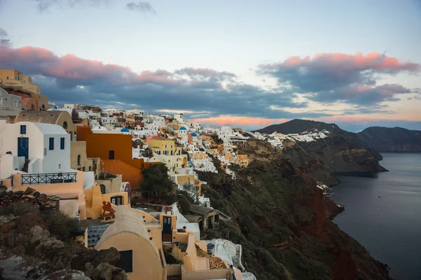 White city on a slope of a hill at sunset, Oia, Santorini, Greec