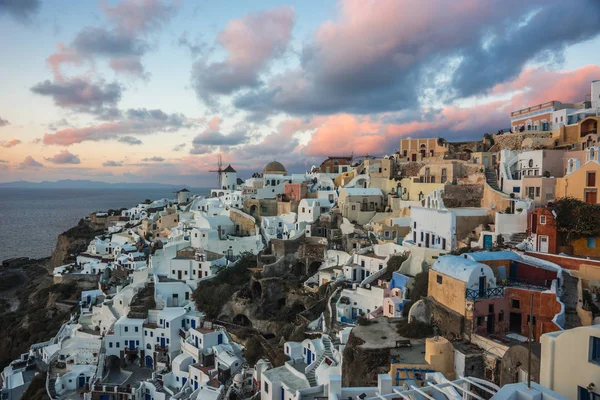 White city on a slope of a hill at sunset, Oia, Santorini, Greec