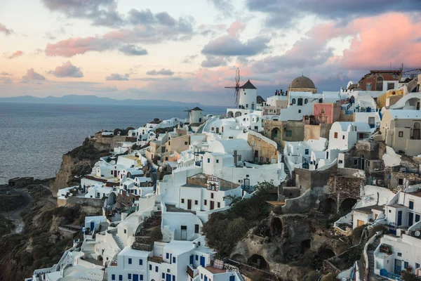 Cidade branca em uma inclinação de uma colina no por do sol, Oia, Santorini, Greec — Fotografia de Stock