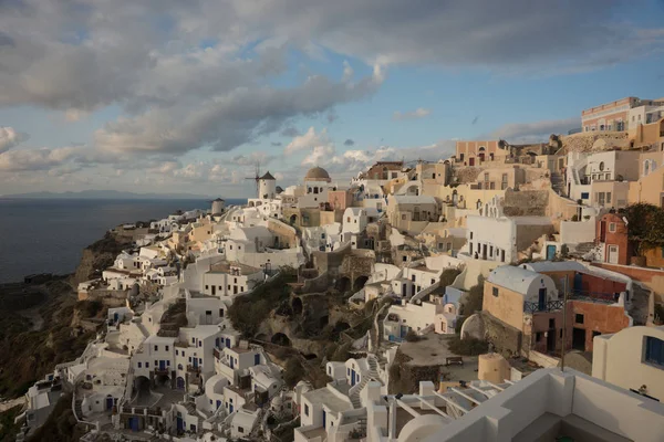 White city on a slope of a hill at sunset, Oia, Santorini, Greec