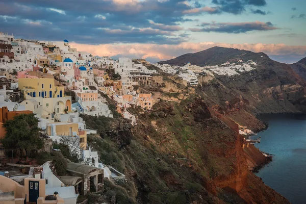 White city on a slope of a hill at sunset, Oia, Santorini, Greec