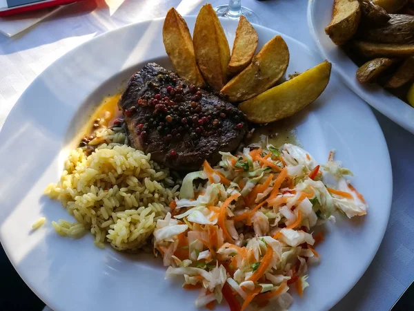 Carne frita en salsa de pimienta con papas, arroz y ensalada — Foto de Stock