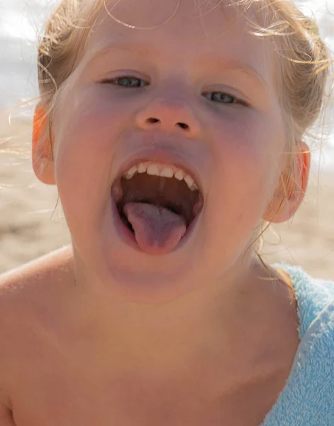 Close-up portrait of a little cheerful girl showing tongue on th — Stock Photo, Image