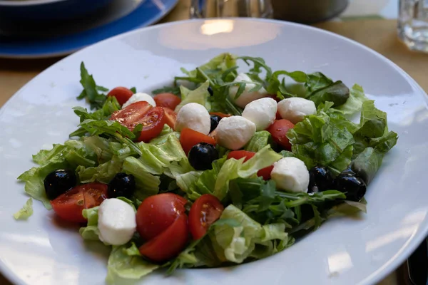 Ensalada de lechuga, rúcula, tomates cherry, mozzarella y negro —  Fotos de Stock