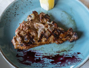 Mavi tabakta domuz bifteği ve bir dilim limon.