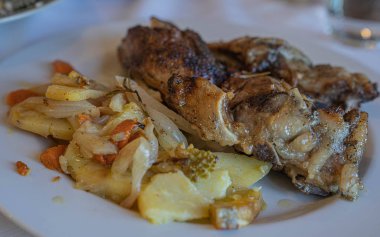 Beyaz tabakta patates ve sebzeli fırında domuz eti