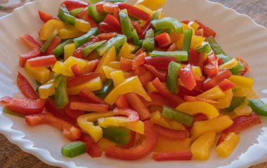 Kırmızı, sarı ve yeşil biber ince dilimlenmiş beyaz bir delikte.