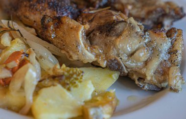 Beyaz tabakta patates ve sebzeli fırında domuz eti