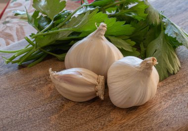 Üç baş sarımsak, dereotlu ve maydanozlu ahşap bir yaban domuzu.