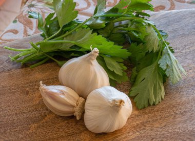 Üç baş sarımsak, dereotlu ve maydanozlu ahşap bir yaban domuzu.