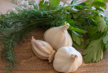 Üç baş sarımsak, dereotlu ve maydanozlu ahşap bir yaban domuzu.