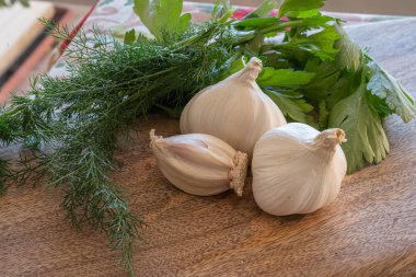 Üç baş sarımsak, dereotlu ve maydanozlu ahşap bir yaban domuzu.
