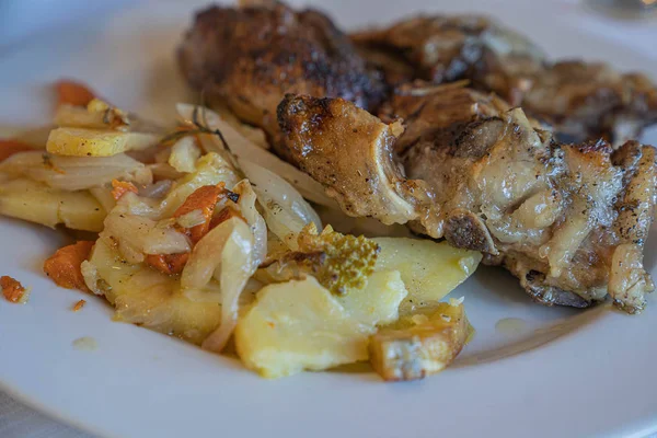 Cerdo al horno con patatas y verduras en un plato blanco — Foto de Stock