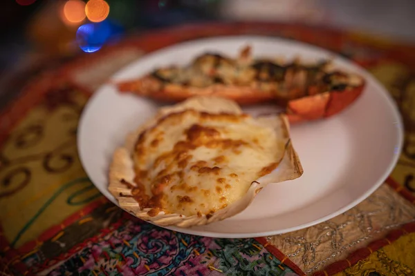 Ψημένο χτένι και αστακός σε λευκό πιάτο με το φως της Πρωτοχρονιάς — Φωτογραφία Αρχείου
