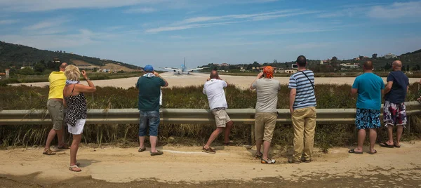 Люди наблюдают за тем, как самолет заходит на посадку низко на острове Фатос. — стоковое фото
