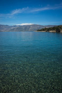 Arkasında karla kaplı dağlar olan deniz manzarası, Gree.