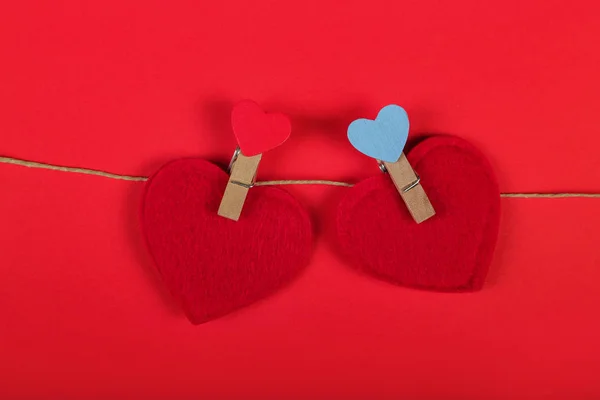 Tarjeta de felicitación para el día de San Valentín. Corazones rojos en la cuerda con pinzas de ropa, sobre fondo rojo. Copiar espacio — Foto de Stock