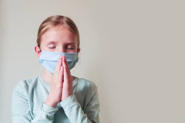 Korunma maskesi takan genç sarışın kız. Coronavirus, covid-2019 Coronavirüs salgınını durdurmak için dua edin.
