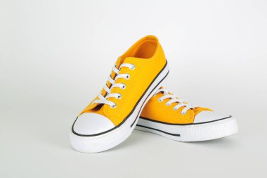 Beyaz arka planda beyaz ayakkabı bağcıkları olan şık sarı spor ayakkabılar.