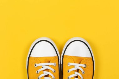 Sarı arka planda beyaz ayakkabı bağcıkları olan şık sarı spor ayakkabılar.