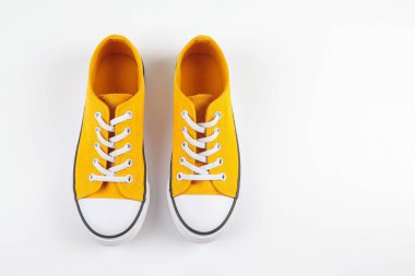 Beyaz arka planda beyaz ayakkabı bağcıkları olan şık sarı spor ayakkabılar.