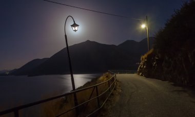 Yol, dağlar, deniz ve ay yakın lambalar ile Gece manzara arka plan olarak vardır. Ay lamba nın ışığı gibi. Village Bali, ada Girit, Yunanistan.