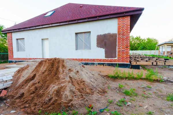 The building with terrace is under construction and a pile of sand