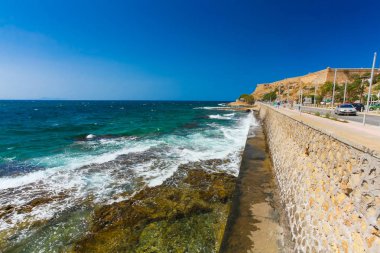 Rethymnon, Island Girit, Yunanistan, - 1 Temmuz 2016: insanlar Leoforos Emmanouil Kefalogianni dolgu üzerinde yürüyor ve denizde izlerken ile berrak zümrüt su ve su altı taş keskin.