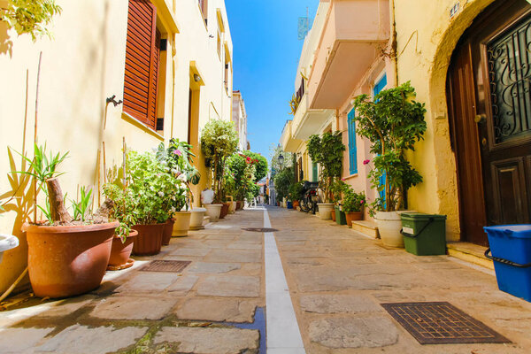 Rethymnon, Island Crete, Greece, - June 23, 2016: The narrow street of Rethymnon (part of Old Town) where there are a lot of pots with flowers